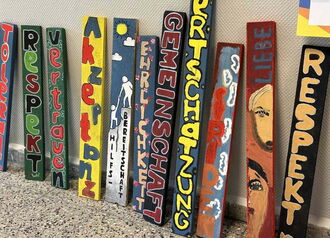 Bunt gestaltete Zaunleisten mit den Werten der Konrad-Wachsmann-Schule – Respekt, Gemeinschaft, Wertschätzung, Hilfsbereitschaft sowie Toleranz und Akzeptanz